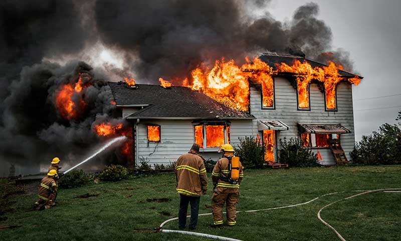 Fire destroying a house as firefighters attempt to put out the flames